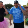 Three men in tutu costumes talking on the phone while greeting each other.