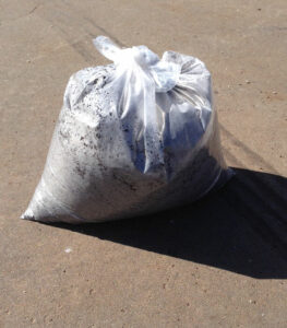 A bag of Potting Mix/Soil 10L Bag sitting on the ground.