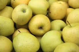 A pile of Malus 'Golden Delicious' Apples with slightly yellowish hues, reminiscent of those from golden delicious apple trees, closely packed together.