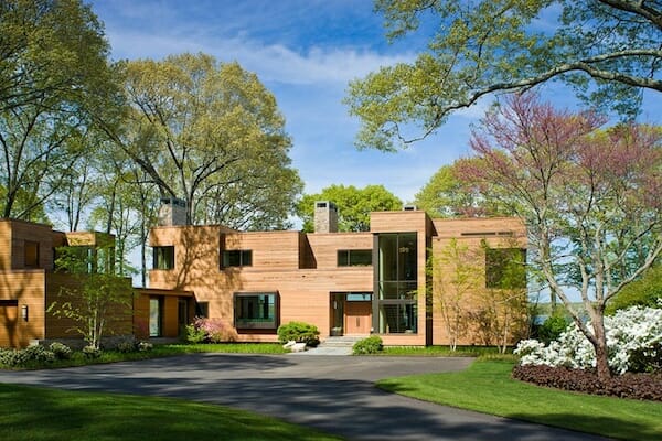 A modern home nestled among giant trees and a lush carpet of grass.