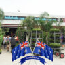 A group of people celebrating Australia Day standing in front of a store with Australian flags.