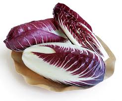 Three Radicchio heads in red and white sit on a round, light-colored plate.