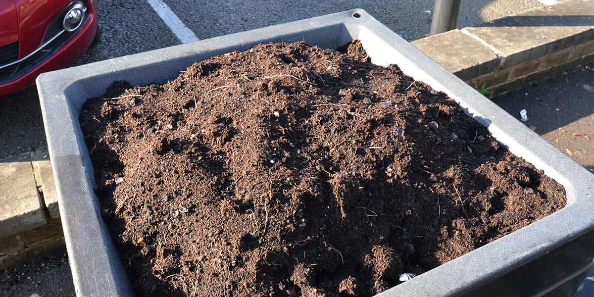A large square pot planter filled with soil