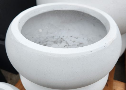 A group of GardenLite Bowl White S 30x13cm concrete pots sitting on a wooden pallet.