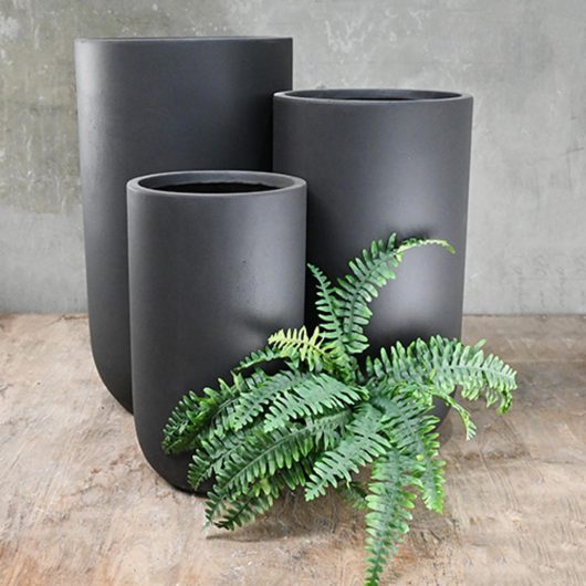 Three GardenLite Corrugated U Pot Black planters on a wooden table. 3 different sizes for plants