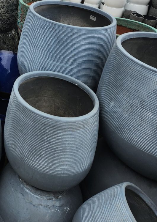 A group of GeoLite Squat Egg Granite XL 55x53cm pots stacked on top of each other.