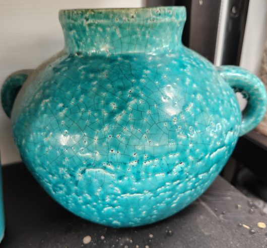 A Tang Urn with Handles Rustic Blue 21x20cm sitting on top of a shelf.