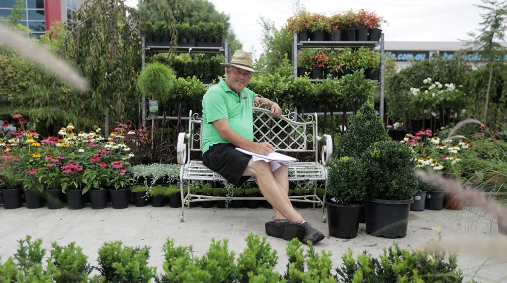 A man enjoying the tranquility of a modern garden center, as he sits on a bench surrounded by stylish greenery.