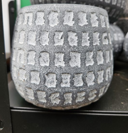 A Dart Squat Dot Congo Grey 15x13cm vase with letters on it sitting on a shelf. pot for plants