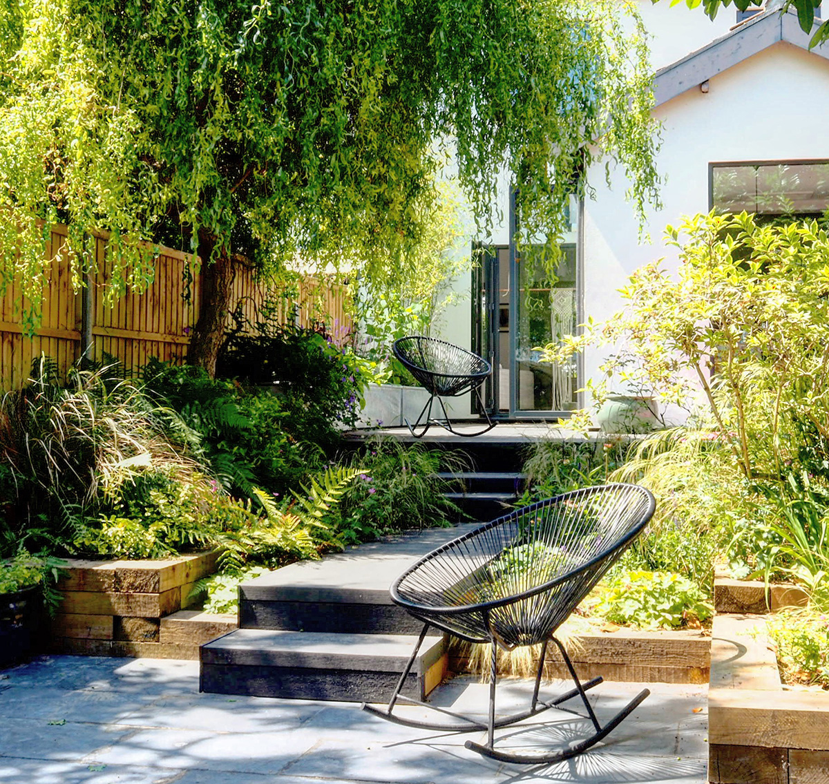 A small garden with a wooden bench and a tree, featuring top indoor plants for added greenery.