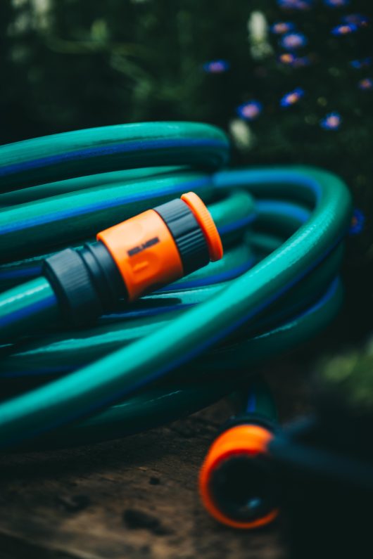 A Hose with Fittings and Tap Connectors 18mmx10m, laying on a wooden table.
