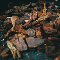 A pile of Searles Mulch Pine Bark 60L on the ground made from wood chips and pine bark.