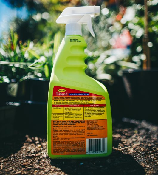 A bottle of Searles Trifend Complete Garden Spray 1L sitting in the dirt. back label