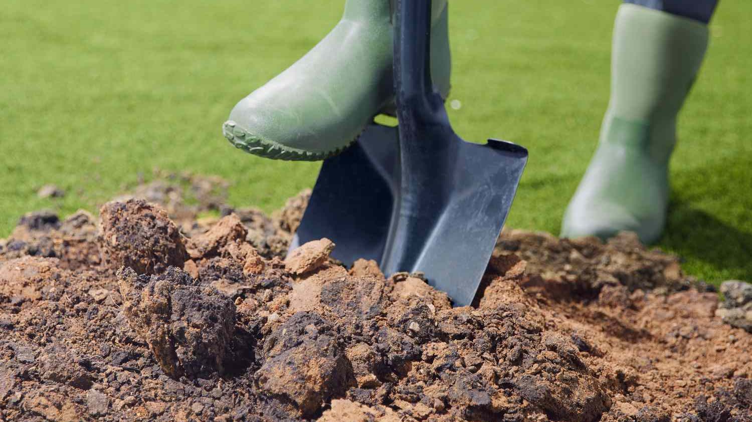 A person engaging in garden design, digging in the dirt with a shovel.