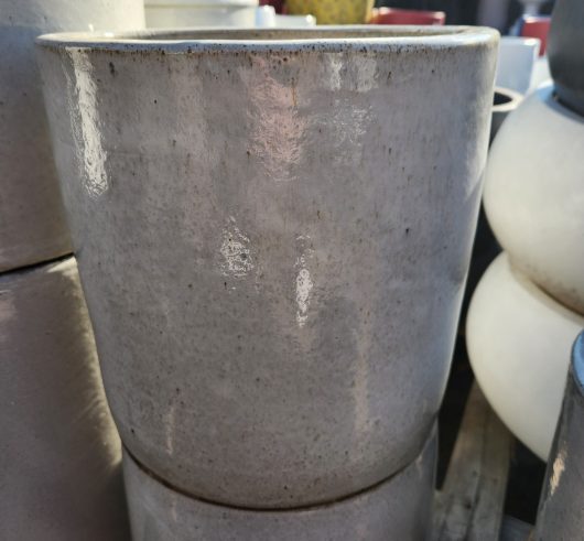 A close-up of the Glazed Cylinder White XL 50x50cm ceramic flower pot with a smooth, shiny finish, stacked atop another identical pot.