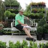 A man enjoying the tranquility of a modern garden center, as he sits on a bench surrounded by stylish greenery.